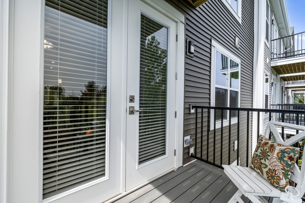 A white door with a window above it and a balcony to the right.