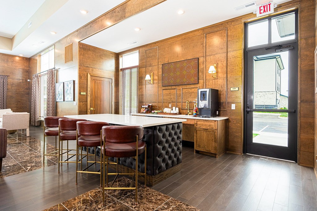 A bar area with a white counter and red chairs.