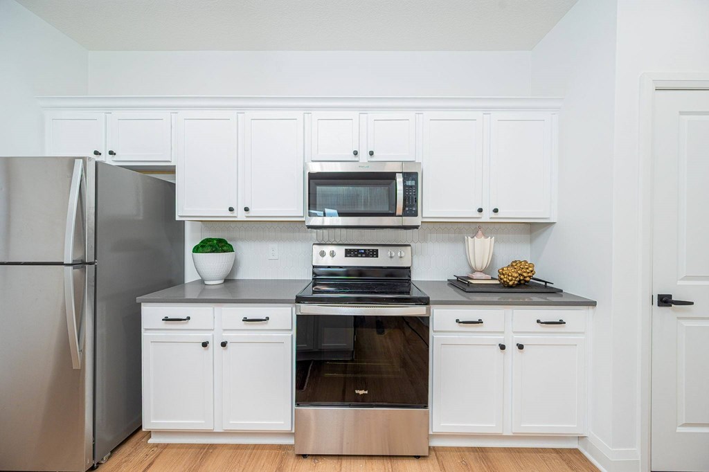 A kitchen with white cabinets and appliances.