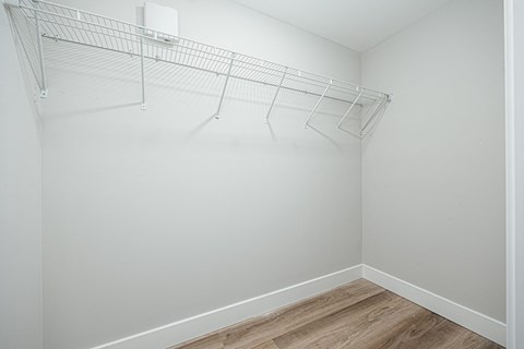 an empty bedroom with a white closet with a wire rack on the wall