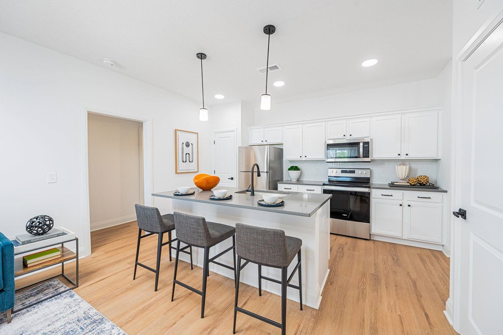A kitchen with a table and chairs in front of it.