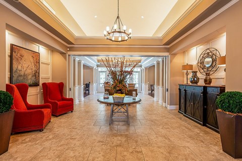 a lobby with red chairs and a table and a chandelier