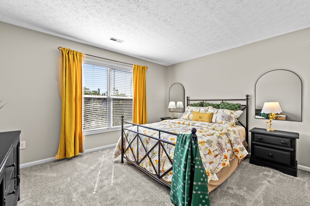 A bedroom with a bed, dresser, and window with yellow curtains.