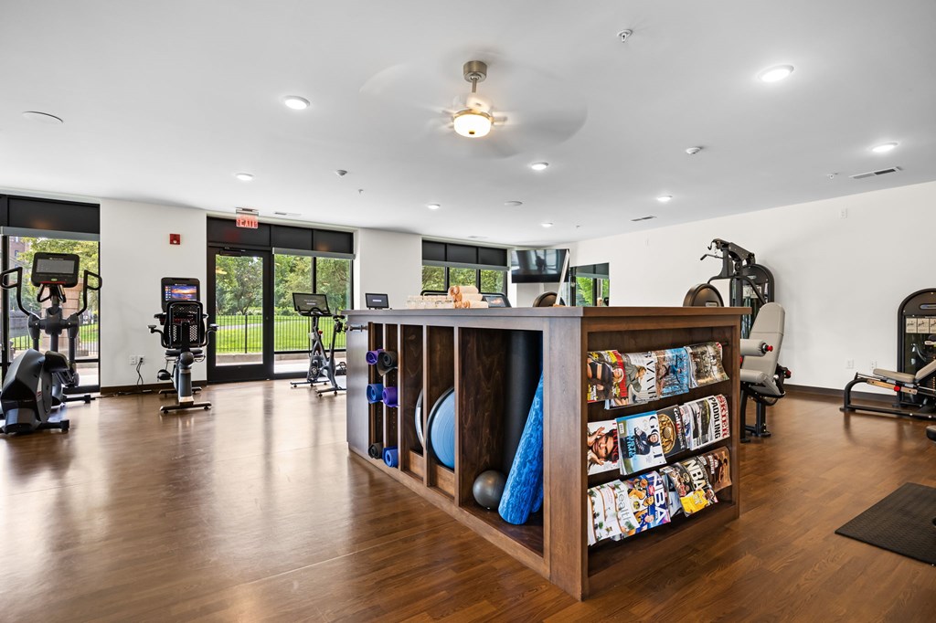 A gym with a variety of equipment and a wooden shelf with colorful items.