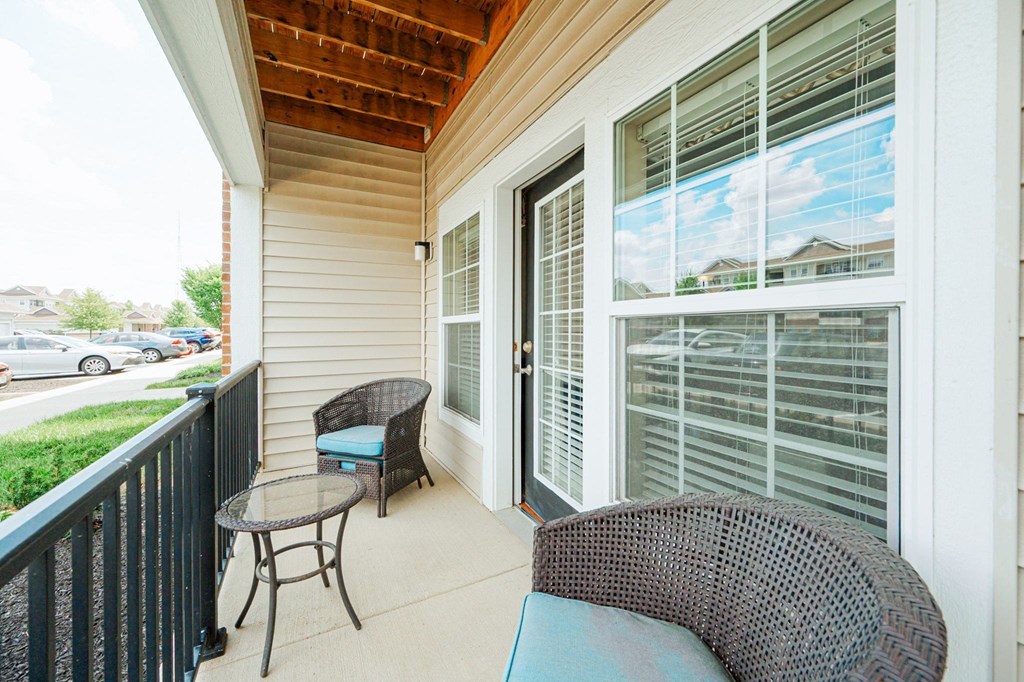 a porch with two chairs and a table and a large window