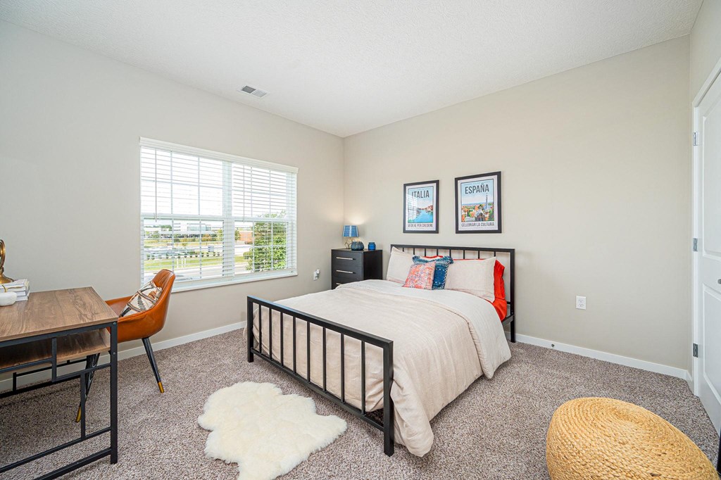 a bedroom with a bed and a desk and a window
