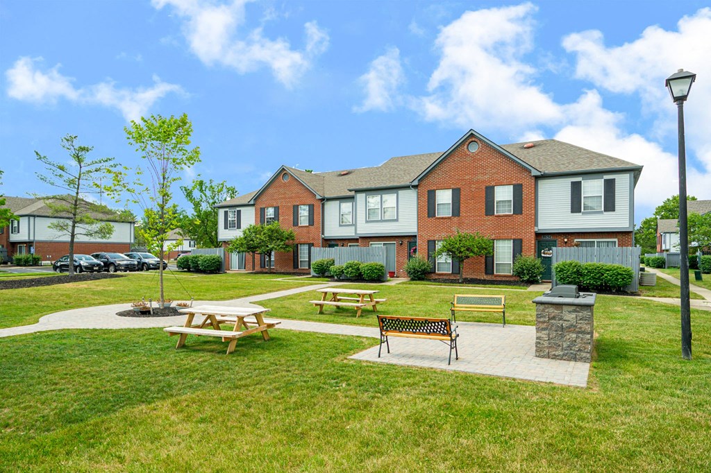 a park with picnic tables in front of a house