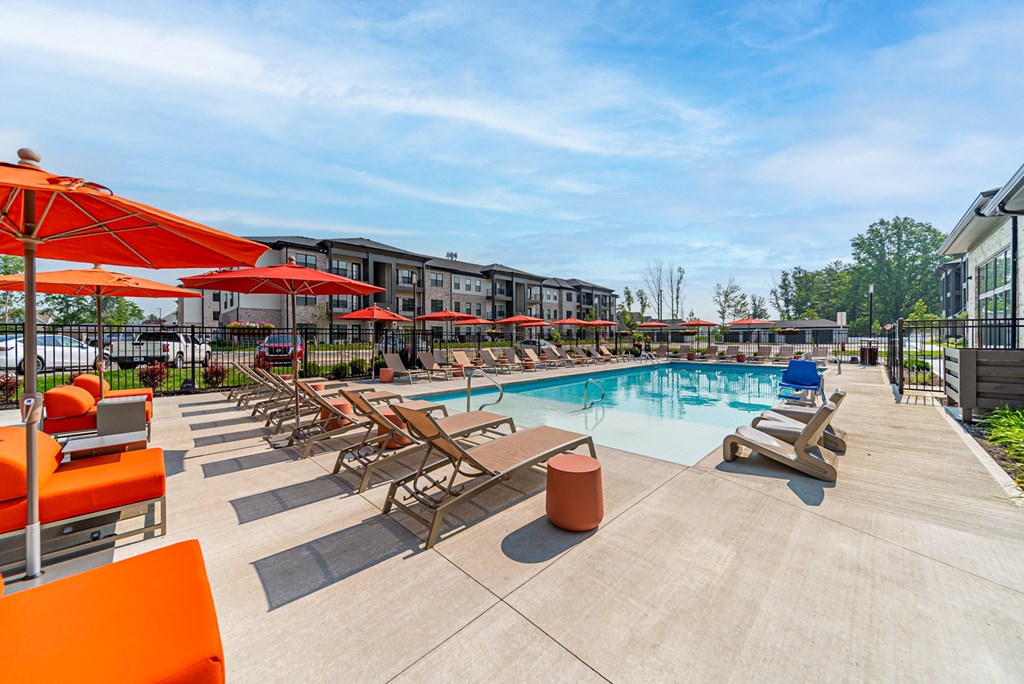 A pool area with sun loungers and umbrellas.