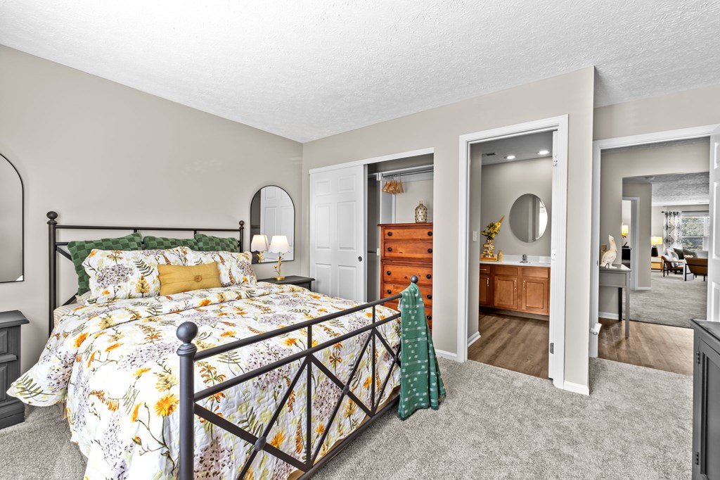 A bedroom with a large bed and a dresser with a mirror.