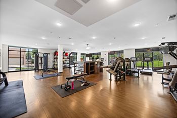 A gym with a variety of equipment including treadmills, weights, and exercise machines.