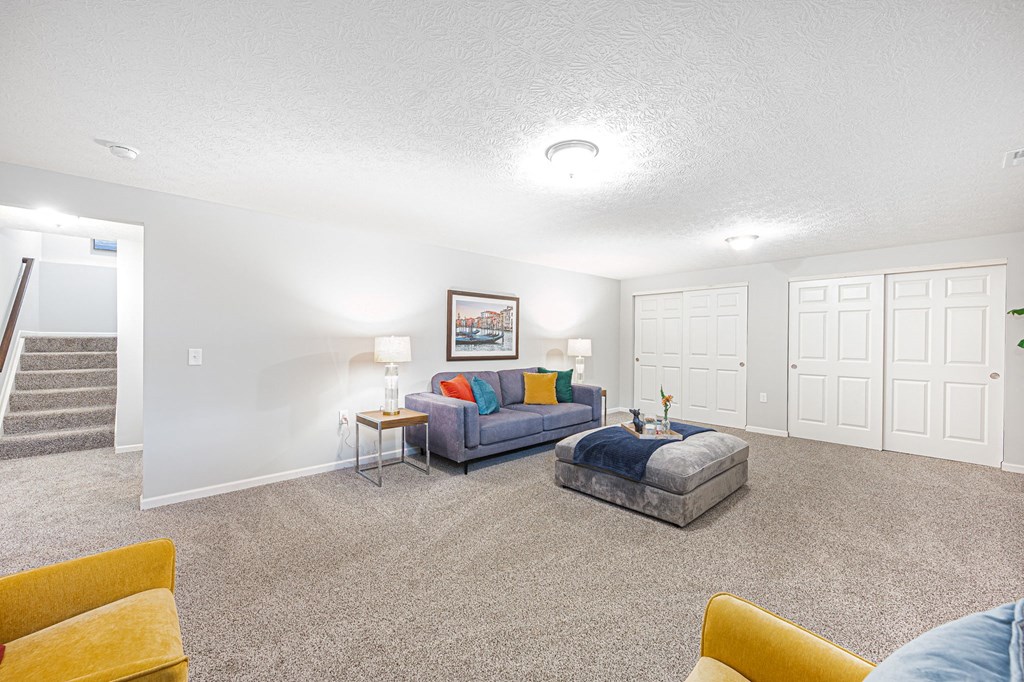 a finished basement with couches and a chair and a table