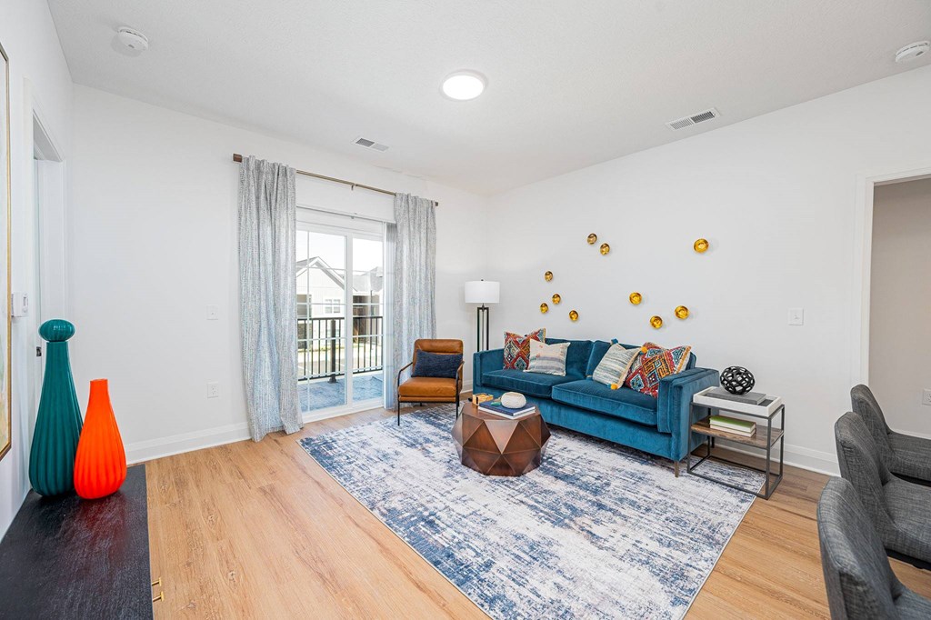 A living room with a blue couch and a rug.