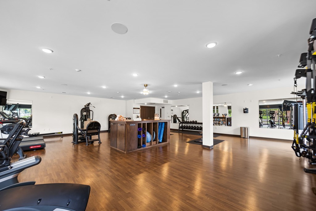 A gym with a variety of equipment including treadmills, weights, and exercise machines.