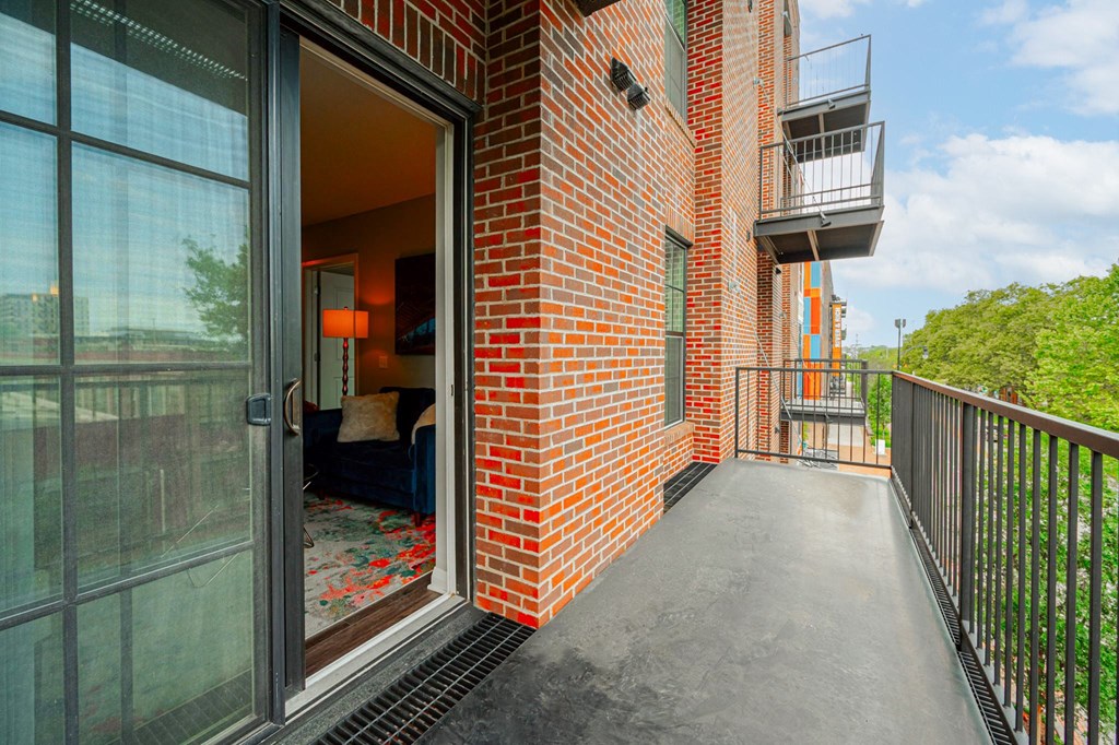 a balcony with a glass door and a brick building