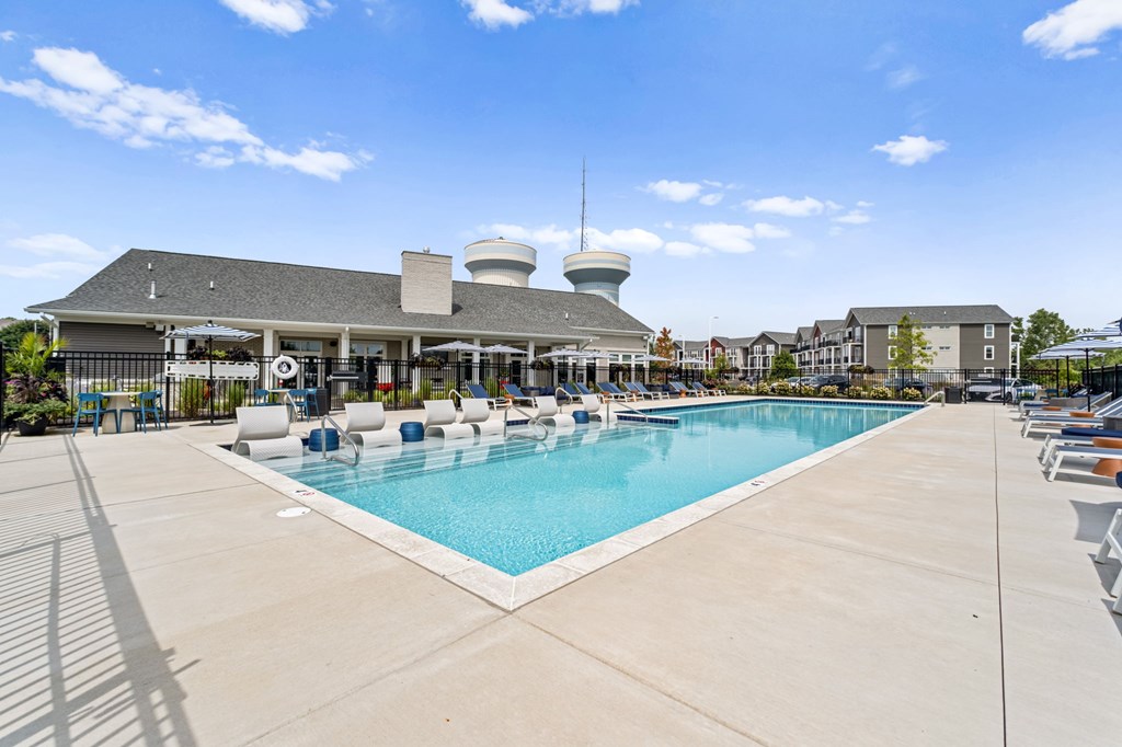 A large outdoor swimming pool with sun loungers and a building with a dome-shaped roof in the background.