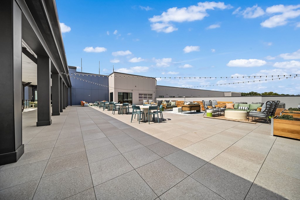A rooftop patio with tables and chairs overlooking a building.