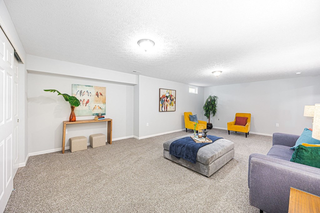 a finished basement with a couch and chairs and a