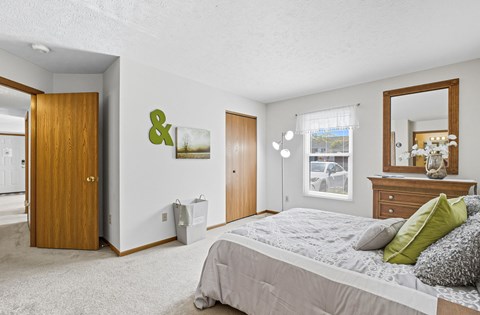 A bedroom with a large bed and a mirror on the dresser.