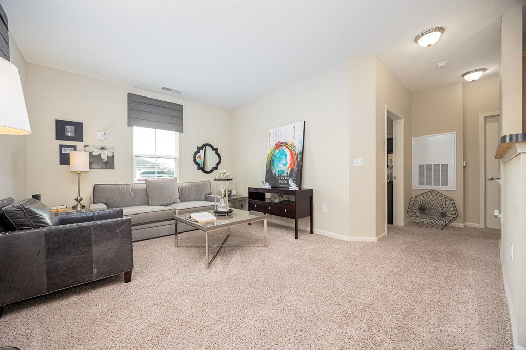 A living room with a grey couch, a coffee table, and a painting on the wall.