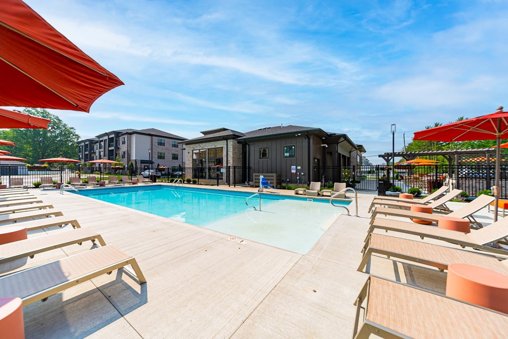 A pool surrounded by sun loungers and umbrellas.