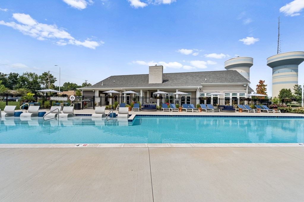 A large swimming pool in front of a building with a white roof.