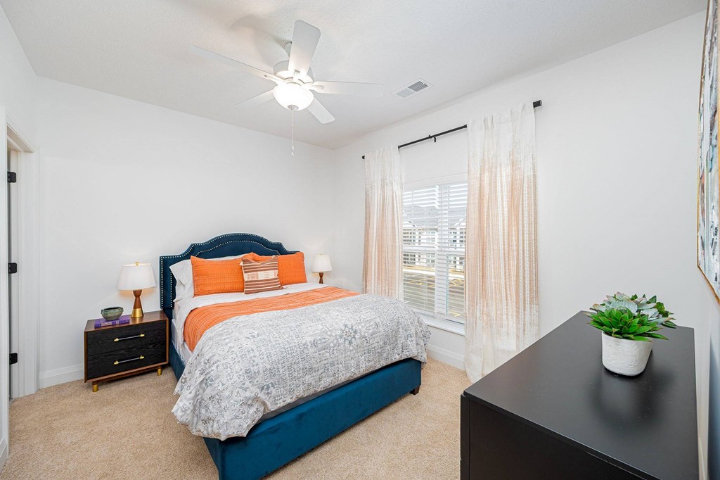 A bedroom with a bed, nightstand, and window.