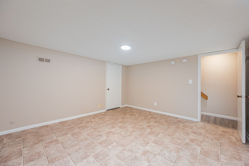 an empty living room with beige walls and a tiled floor