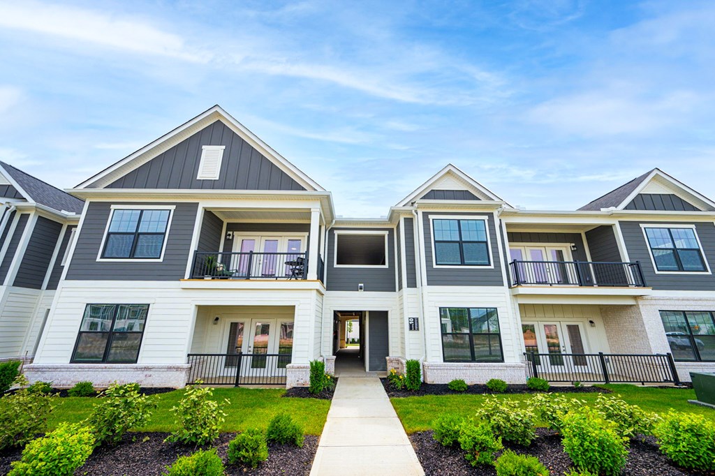 A modern two-story house with a front yard and a clear sky.