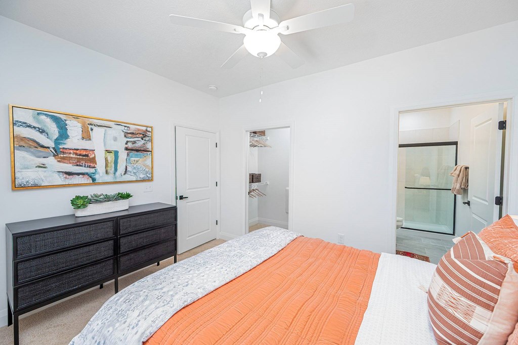 A bedroom with a bed, dresser, and painting on the wall.