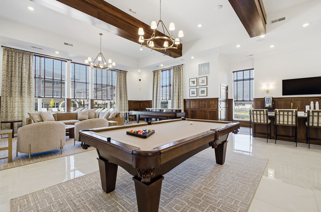 A large billiard table is in the middle of a spacious room with a pool table and a couch.