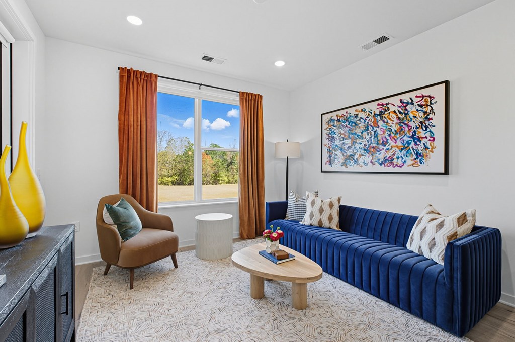 A living room with a blue couch, a brown chair, a coffee table, and a painting on the wall.