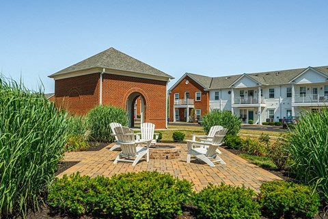 a brick patio with two chairs and a fire pit in front of a brick building