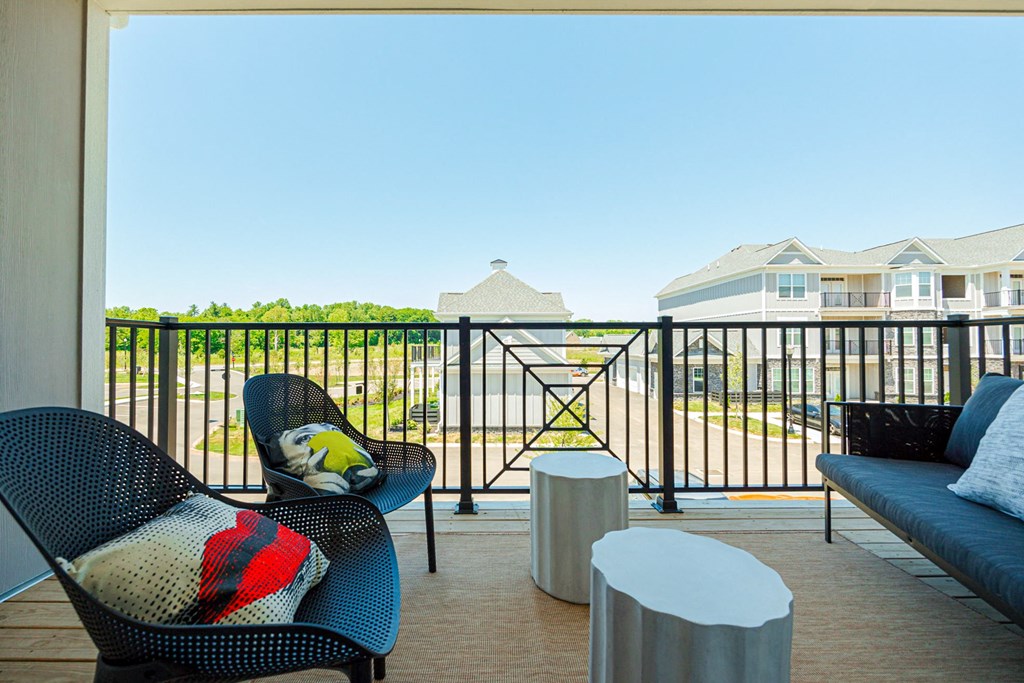 a balcony with chairs and tables and a view of a yard and houses