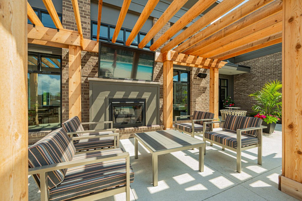 a covered patio with chairs and a fireplace