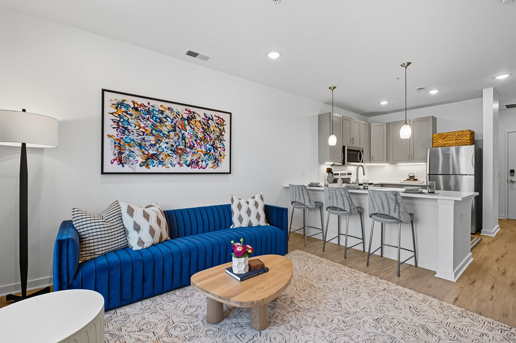 A blue couch with a white and grey pillow sits in a living room with a coffee table in front of it.