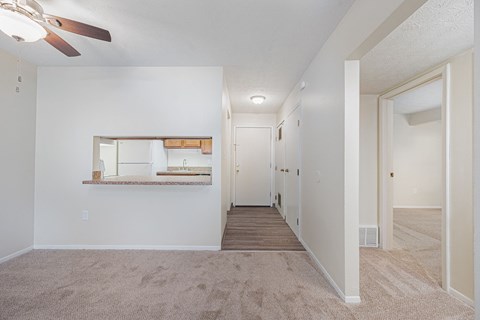 an empty living room and hallway with a ceiling fan