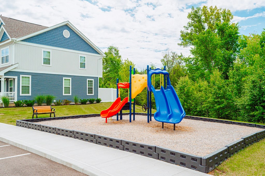 a playground with two slides in front of a house