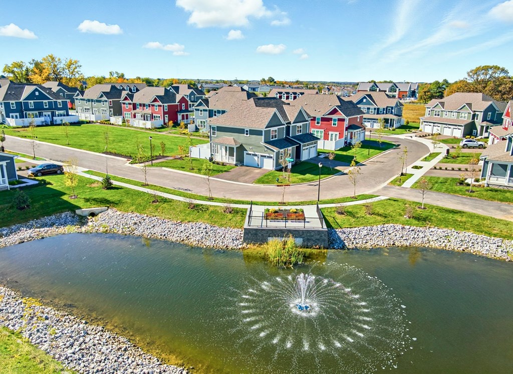 A fountain in the middle of a pond in a residential area.
