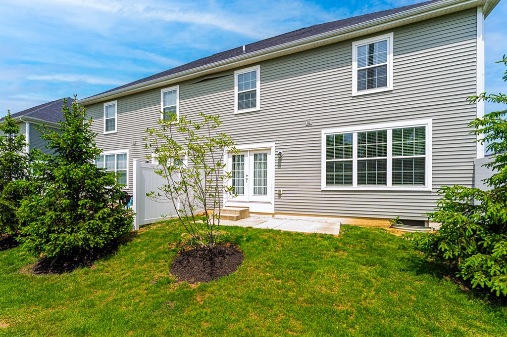 A grey house with a tree in front of it.