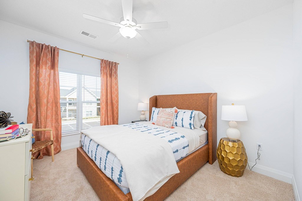 A bedroom with a bed, nightstand, and window with curtains.