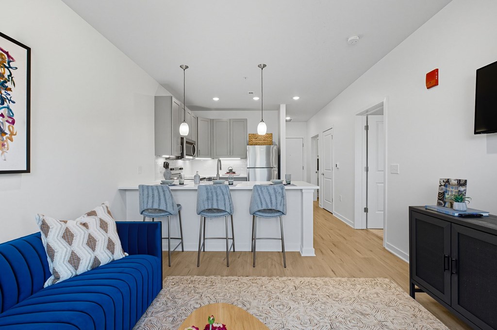 A blue couch sits in a living room with a kitchen in the background.