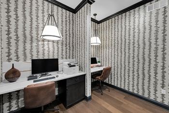 A room with a desk and a chair with a patterned wallpaper.