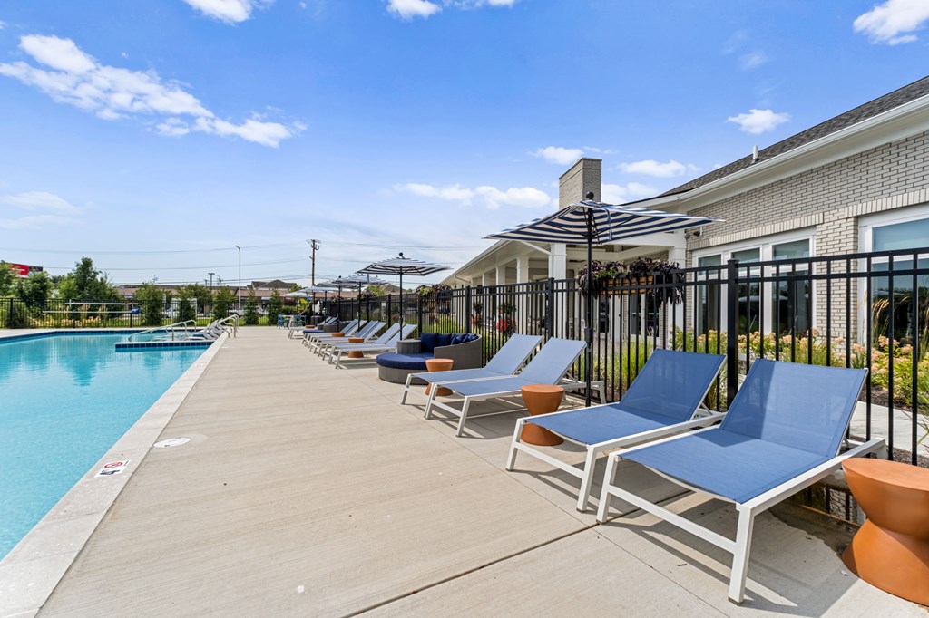 A poolside area with sun loungers and a building in the background.