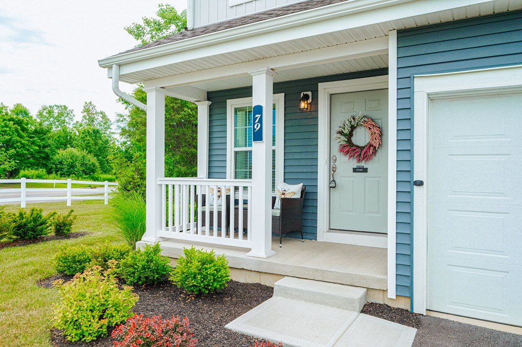the front porch of a blue house with a white door
