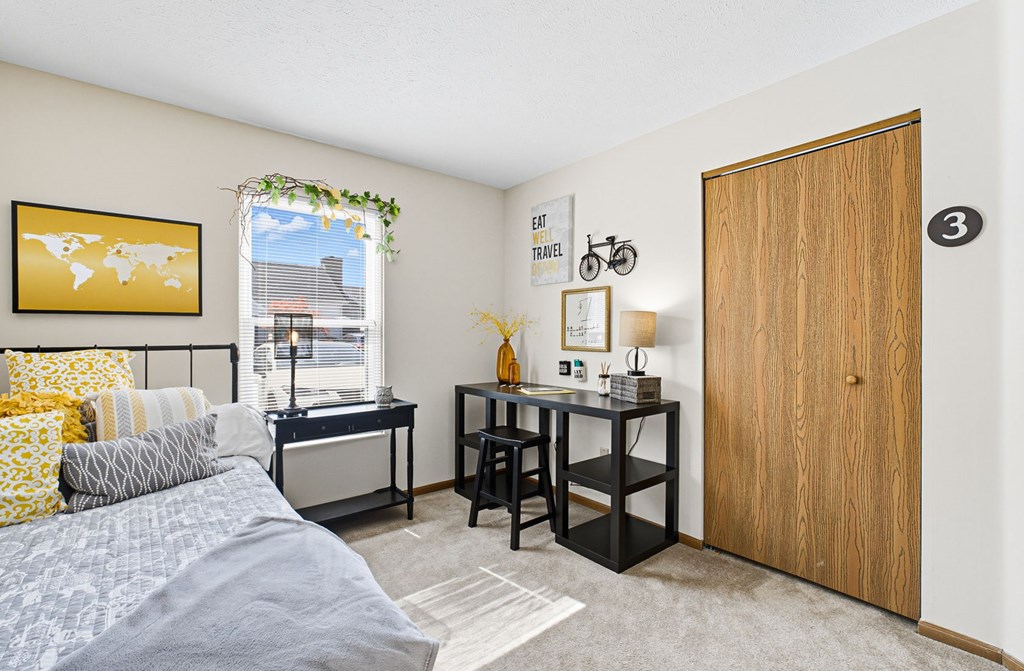 A bedroom with a bed, desk, and chair.