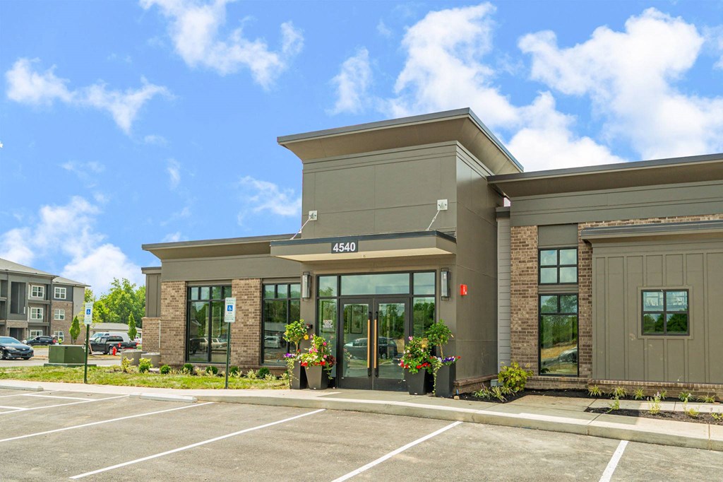 the front of a building with glass doors and a parking lot