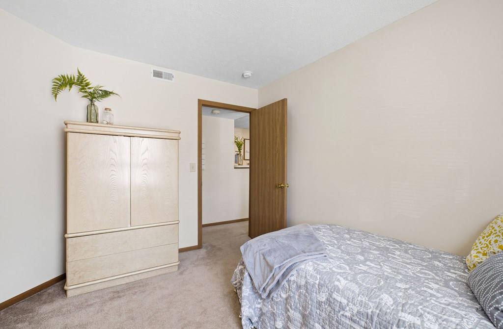 A bedroom with a bed, dresser, and mirror.