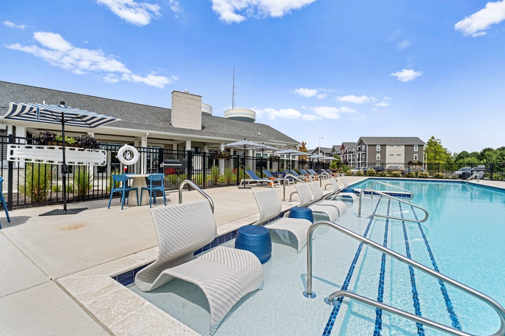 A swimming pool with blue water and white lounge chairs.
