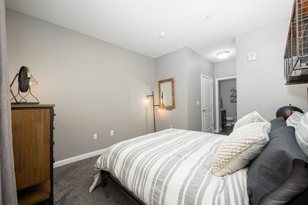 a bedroom with a bed and a dresser and a bathroom