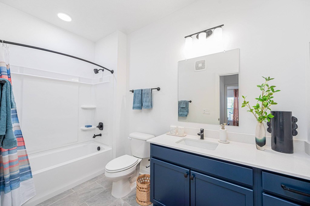 A bathroom with a white tub, blue sink, and a mirror.